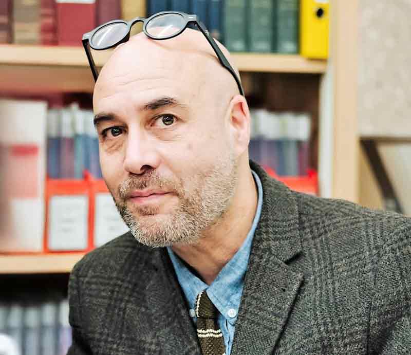 In a library with traditional green tweed jacket.